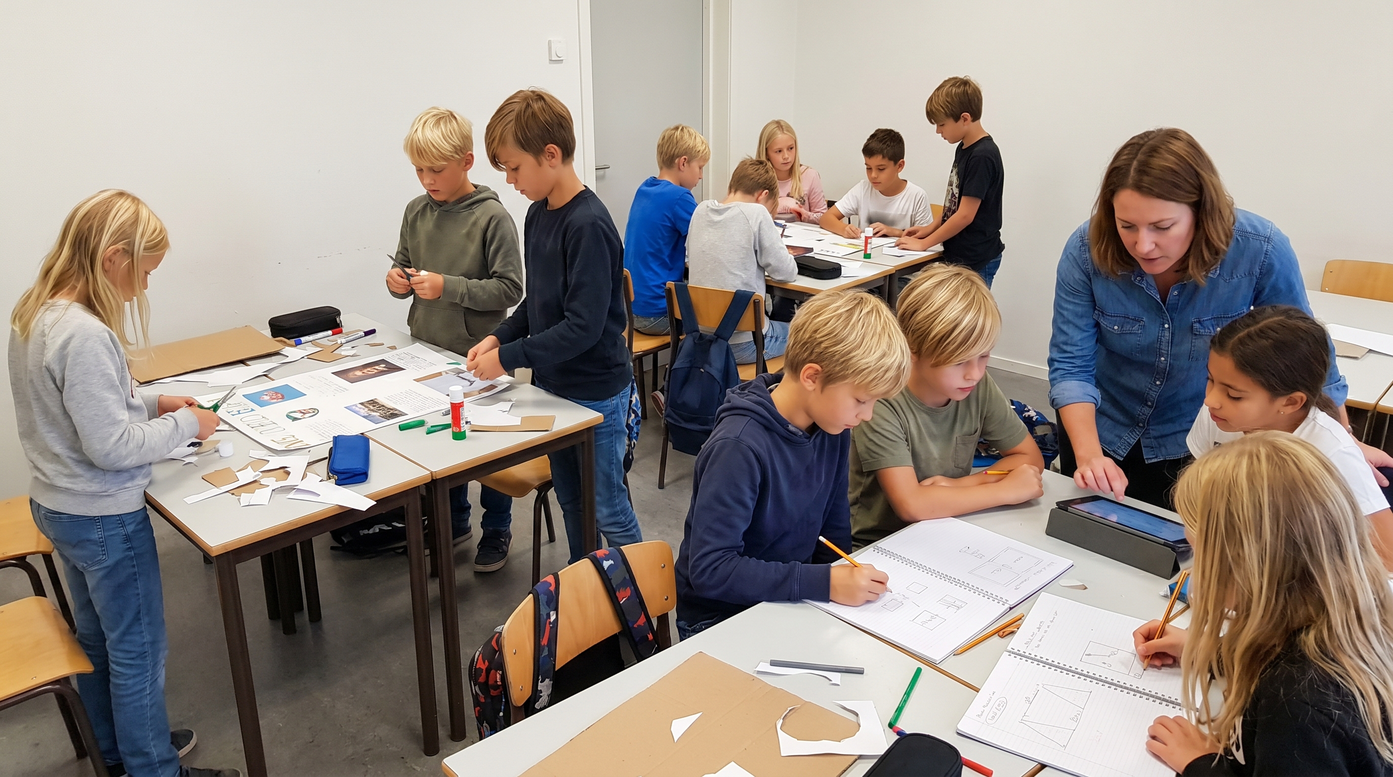 Schulkinder arbeiten in Kleingruppen an einem Projektwochen-Plakat im Klassenzimmer