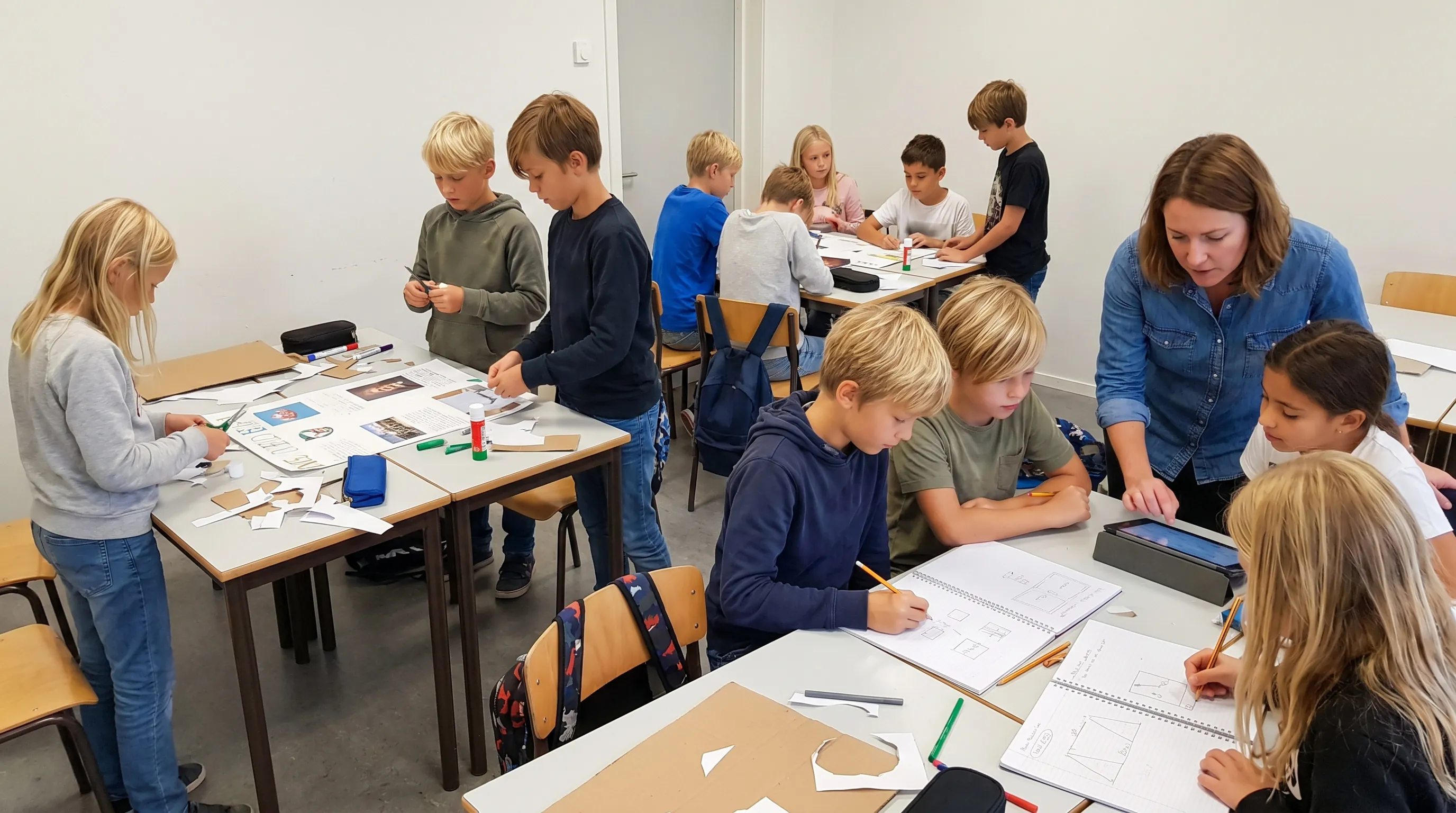 Schulkinder arbeiten in Kleingruppen an einem Projektwochen-Plakat im Klassenzimmer